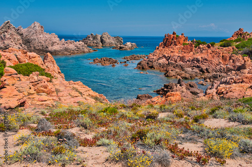 the red porphyry rocks of Cala Cannedi in northern Sardinia (Italy) on a hot summer day with blue skies