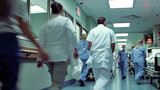 This dynamic image shows healthcare workers rushing through a hospital hall, highlighting the essential, fast-paced work they do