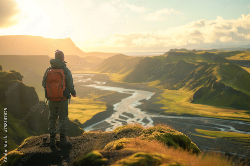 Young hiker with heavy backpack admiring scenic view of spectacular Icelandic nature on a sunset. Breathtaking landscape of Iceland. Hiking by foot.