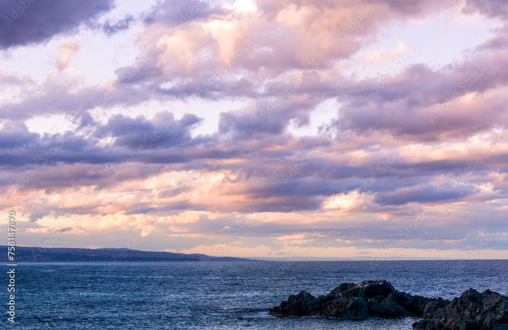 amazing evening or morning sea shore landscape of blue water, rock coast and unique natural phenomenon of glow from below the sea to amazing sunset colorful clouds