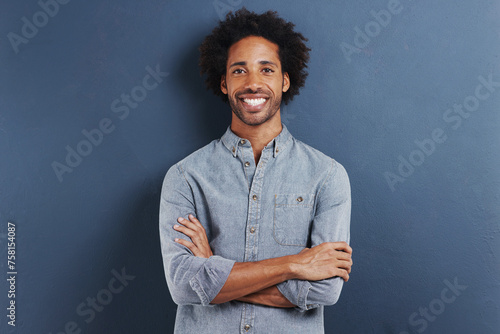Portrait, smile and black man with arms crossed, fashion and afro on a blue studio background. Face, African person and model with casual outfit and stylish clothes with confidence and mockup space