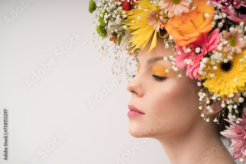 Fototapeta Naklejka Na Ścianę i Meble -  A side profile of a woman with eyes closed, her features softened by the surrounding bloom of a colorful floral crown. The peaceful expression invites a sense of calm.