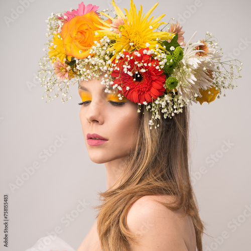 Fototapeta Naklejka Na Ścianę i Meble -   A portrait of a woman crowned with a vibrant mix of flowers, her expression serene amidst the colorful arrangement. The blooms convey joy and natural beauty.