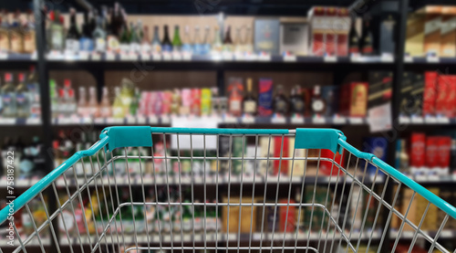 Green shopping cart with blurred image of alcohol store in background. (Selective focused at shopping cart)	
