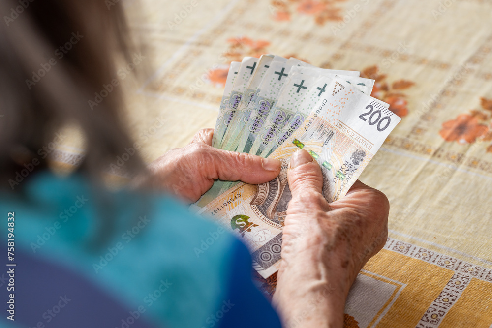 Polish old woman holds a pension in her hands, Economic concept, Home budgets of pensioners in Poland, rising costs of living, 13th and 14th pension