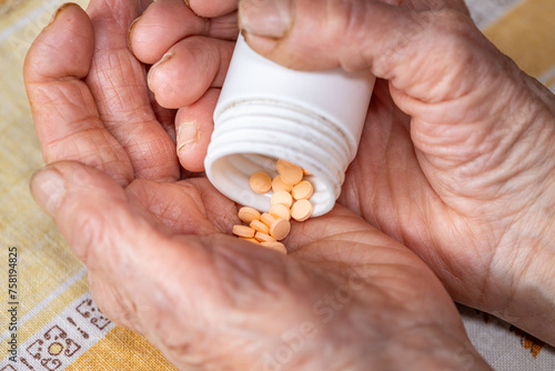 Obraz na płótnie Elderly Woman's Hands and Orange Pills, Health Concept, Medicines Related to Older People's Ailments. Ailments related to dementia, schizophrenia or psychotic diseases w salonie