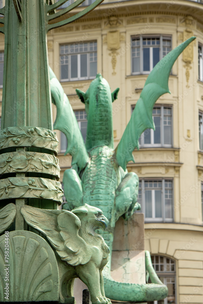 Fototapeta premium Ljubljana, Slovenia; The Ljubljana Dragon Bridge spans the Ljubljanica River, Ljubljana Central Market and Saint Nicholas's Cathedral (Katedrala Sv. Nikolaj), dragon sculpture