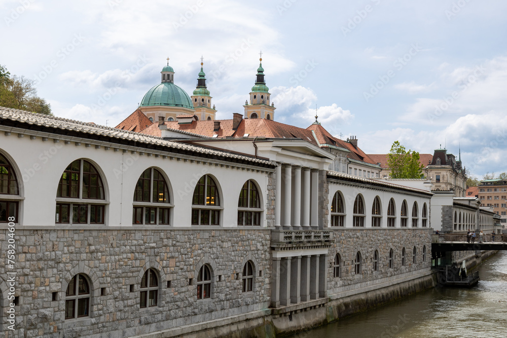 Ljubljana, Slovenia;  The Ljubljana Dragon Bridge spans the Ljubljanica River, Ljubljana Central Market and Saint Nicholas's Cathedral (Katedrala Sv. Nikolaj), dragon sculpture