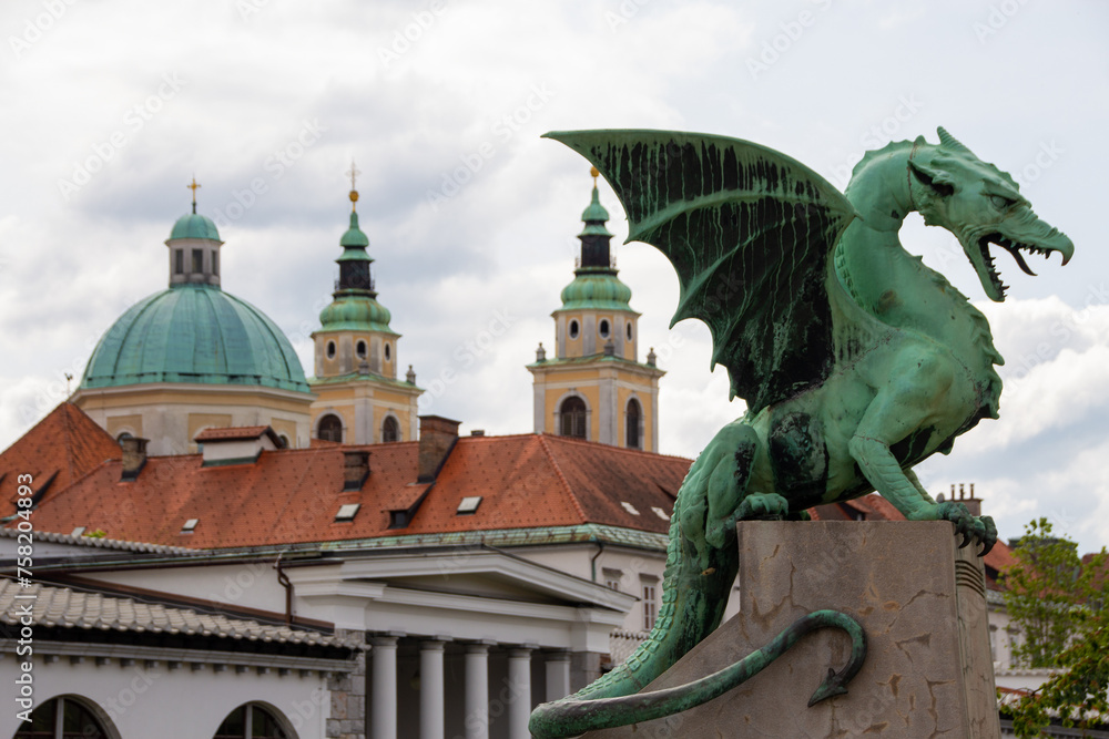 Obraz premium Ljubljana, Slovenia; The Ljubljana Dragon Bridge spans the Ljubljanica River, Ljubljana Central Market and Saint Nicholas's Cathedral (Katedrala Sv. Nikolaj), dragon sculpture