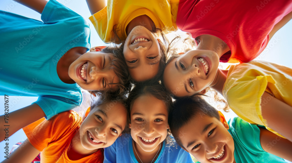 Fototapeta premium High-angle shot of a group of children forming a circle and looking up towards the camera with smiling faces.