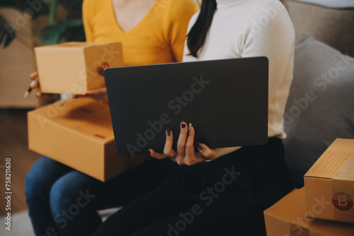 Asian SME business women use laptop computer checking customer order online shipping boxes at home. Starting Small business entrepreneur SME freelance. Online business, Work at home concept.