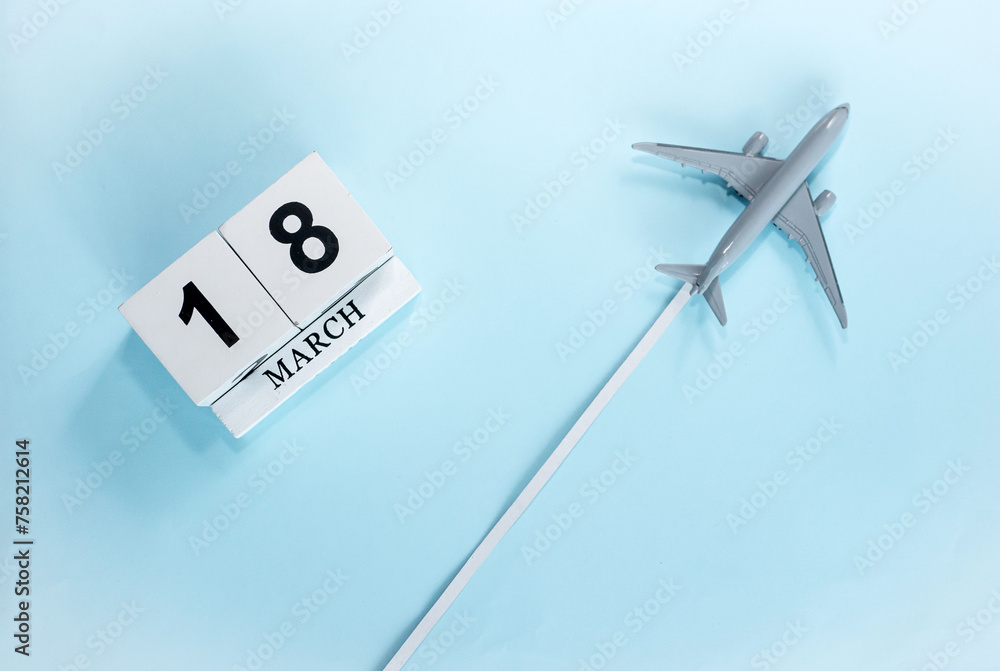 March calendar with number 18. Top view of a calendar with a flying passenger plane. Scheduler. Travel concept. Copy space. March calendar with number 18. Top view of a calendar with a flying passenger plane. Scheduler. Travel concept. Copy space.