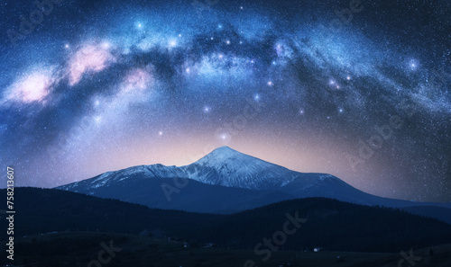Milky Way over the beautiful Goverla mountain with snow covered peak at night in summer in Ukraine. Colorful landscape with bright starry sky with Milky Way arch, snowy rocks, hills. Space. Nature © den-belitsky