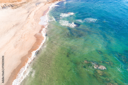 shore of a beach with turquoise waters seen from a drone.