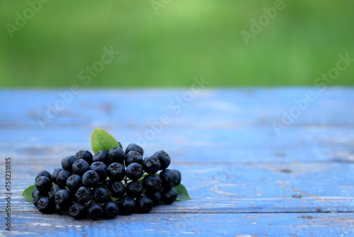 Chokeberries, aronia fruits on bokeh blue wooden background with space for text, bokeh empty space, fruits on natural background. photo