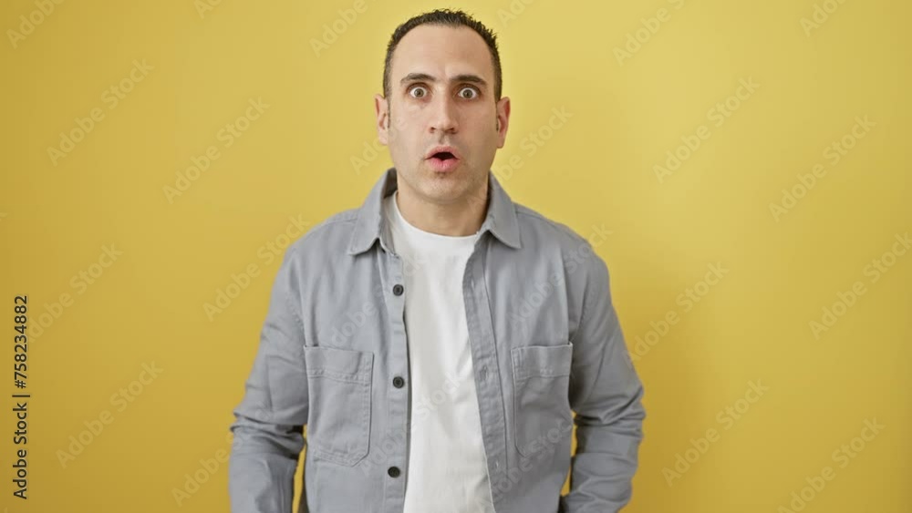 Hispanic guy, stunned and afraid, shocked beyond belief! fully expressing a surprise, fear-struck face. wearing shirt, standing alone on a yellow backdrop. Hispanic guy, stunned and afraid, shocked beyond belief! fully expressing a surprise, fear-struck face. wearing shirt, standing alone on a yellow backdrop.