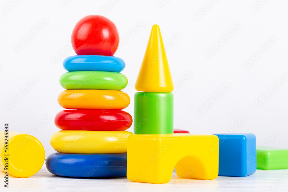 Colored plastic children's pyramid and cubes on white background, copy space. Educational baby toy. Colored plastic children's pyramid and cubes on white background, copy space. Educational baby toy.