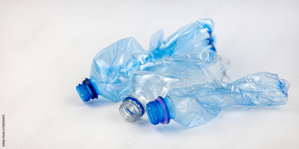 Fototapeta premium Crumpled used mineral water bottles on a white background. The concept of waste sorting.