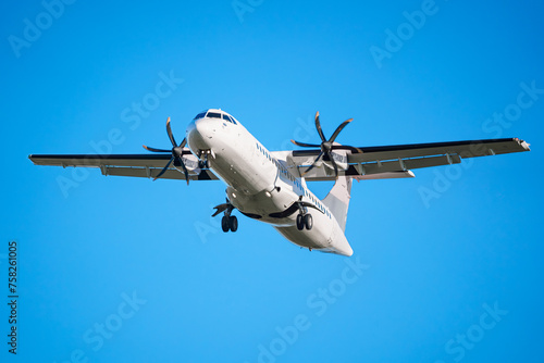 ATR 72 airplane, a twin-engine turboprop short-haul regional passenger aircraft. Landing airplane. Blue background. photo