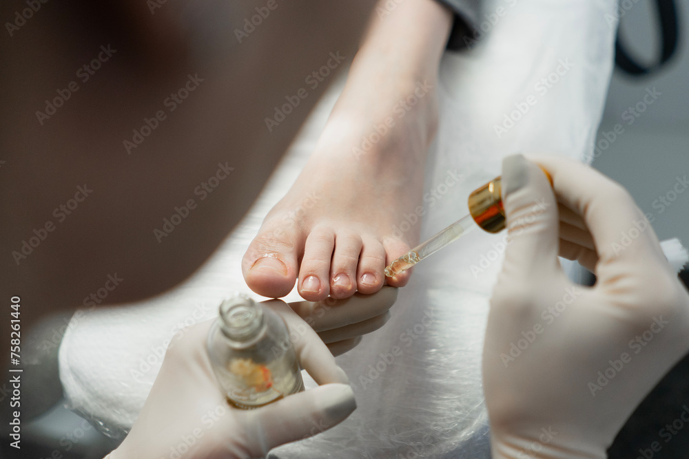 A pedicure master does cleaning and massage, pedicure, to a young beautiful girl with a small foot. Caring for female beauty in a beauty salon during a procedure. Skin of feet and toes close-up - obrazy, fototapety, plakaty 