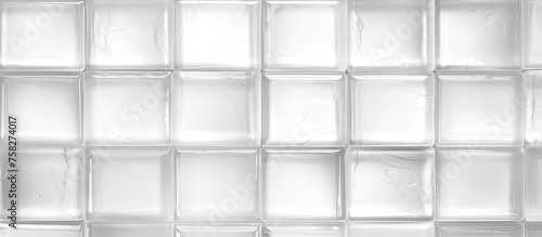A close up of a brown rectanglular wall made of clear glass cubes, with grey flooring. The material property reflects tints and shades in parallel patterns, creating symmetry and a modern aesthetic
