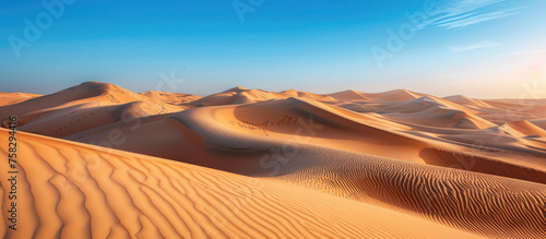 Vast desert landscape with undulating golden sand dunes, clear blue sky & hint of footsteps, symbolizing adventure and tranquility © Mik Saar