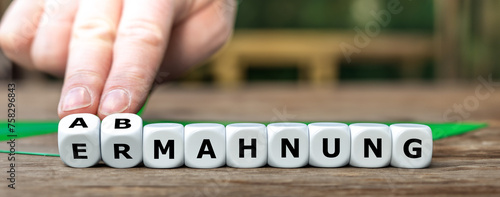 Foto Hand dreht Würfel und ändert das Wort 'Ermahnung'  in 'Abmahnung'