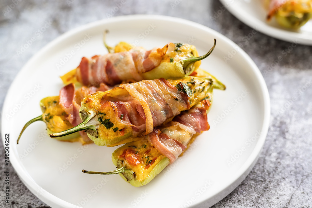 Green paprika appetizer in a plate, green pepper halves stuffed with cheese and wrapped in bacon close up Green paprika appetizer in a plate, green pepper halves stuffed with cheese and wrapped in bacon close up