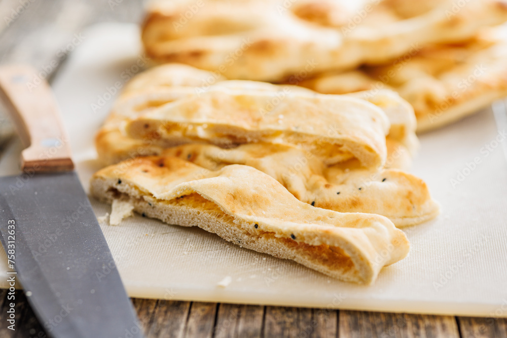 Freshly Baked Naan Bread on cutting board on wooden table Freshly Baked Naan Bread on cutting board on wooden table