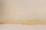 Gold glitter Ink watercolor blot on beige grain empty paper texture background.