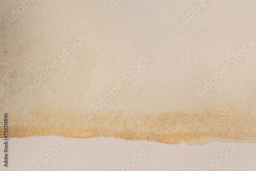 Gold glitter Ink watercolor blot on beige grain empty paper texture background. © Liliia