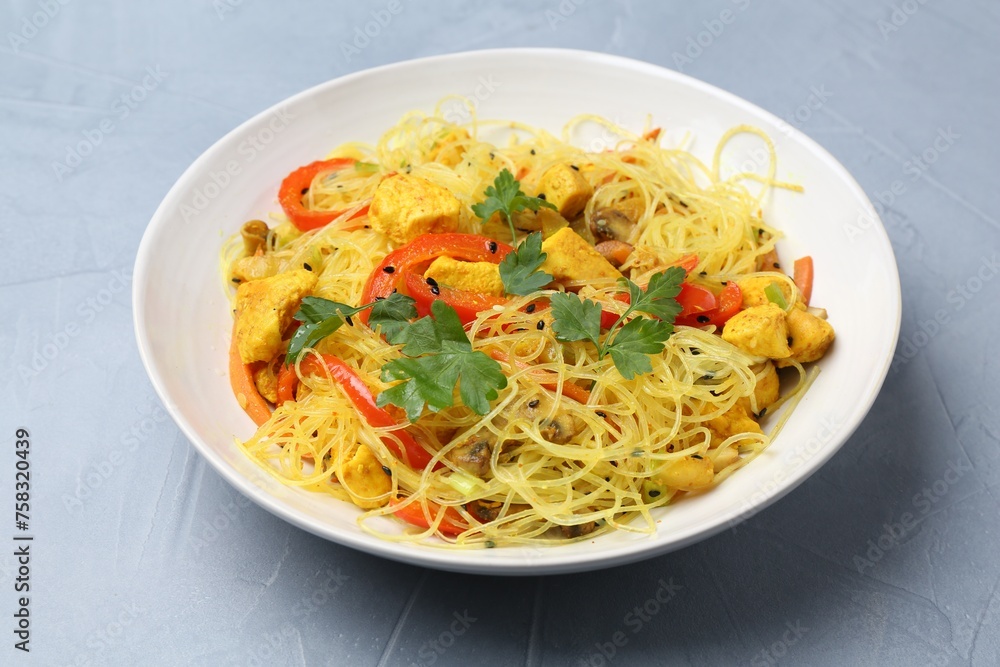 Stir-fry. Delicious cooked noodles with chicken and vegetables in bowl on gray table, closeup Stir-fry. Delicious cooked noodles with chicken and vegetables in bowl on gray table, closeup