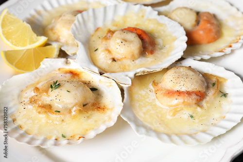 Fried scallops in shells and lemon on plate, closeup