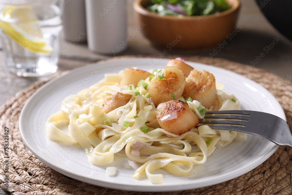 Delicious scallop pasta with onion served on table, closeup