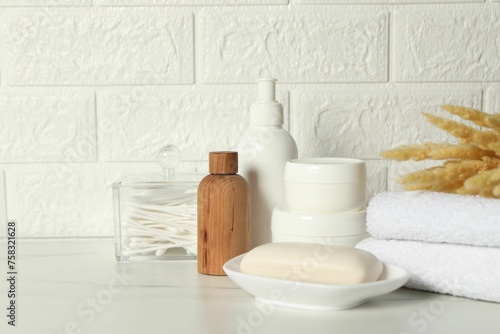 Fototapeta Naklejka Na Ścianę i Meble -  Different bath accessories, personal care products and spikelets on white table near brick wall