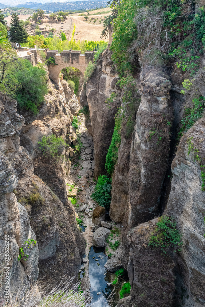 View of old stone arched Puente Viejo bridge crossing rocky river in mountainous valley in Ronda, Andalusia, Spain View of old stone arched Puente Viejo bridge crossing rocky river in mountainous valley in Ronda, Andalusia, Spain