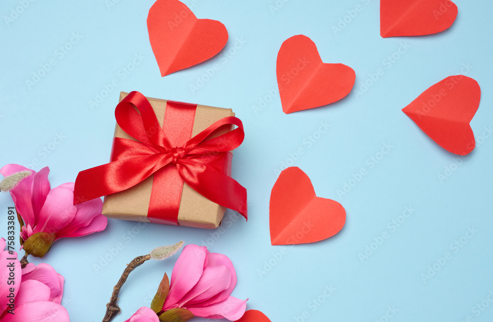 Box tied with a red ribbon and small hearts on a blue background