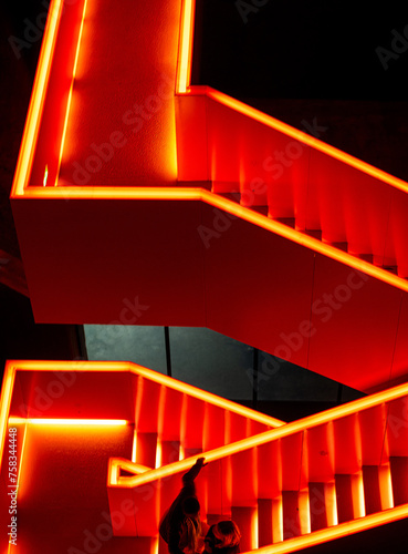 Red illuminated metal staircase at night on the industrial site