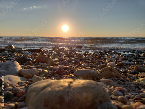 Majestic sunset at New Brunswick beach with wavy water ocean water and stones covering the entire shore