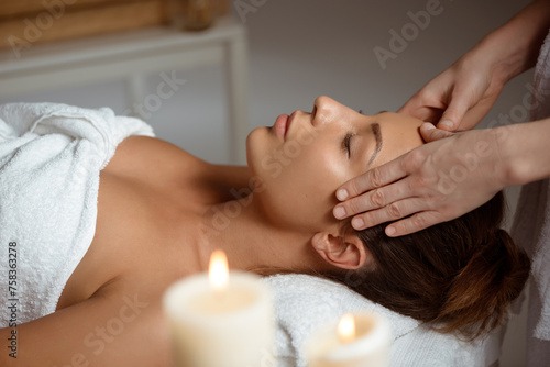 young woman having face massage relaxing in spa salon
