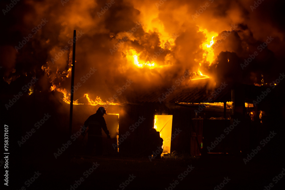 night fire in the forest, a residential wooden house is burning in flames