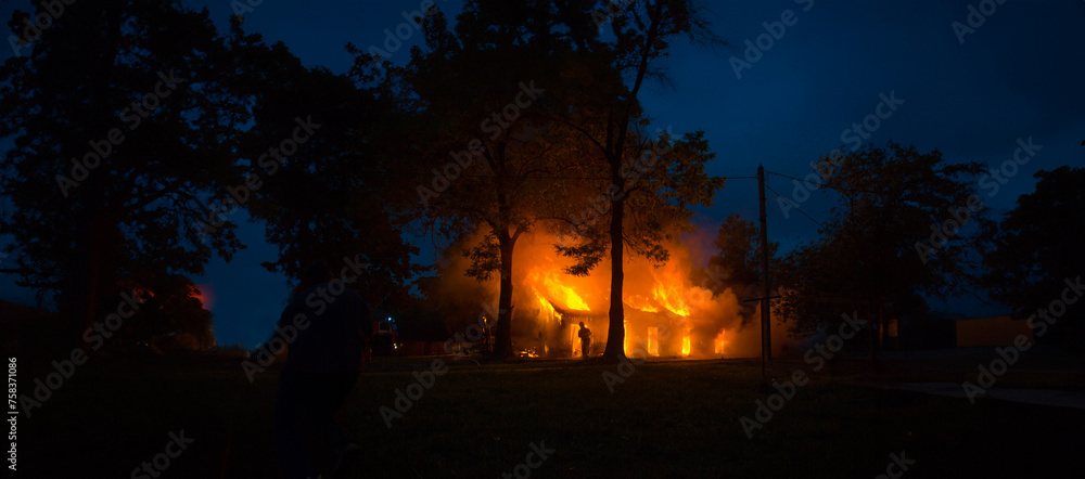 night fire in the forest, a residential wooden house is burning in flames night fire in the forest, a residential wooden house is burning in flames