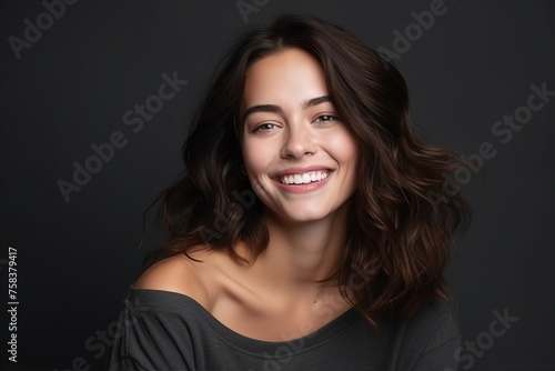 Portrait of a beautiful smiling young woman on a dark background.