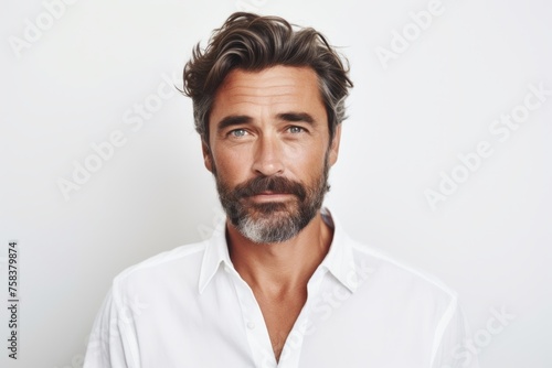 Handsome bearded man in white shirt looking at camera with serious expression