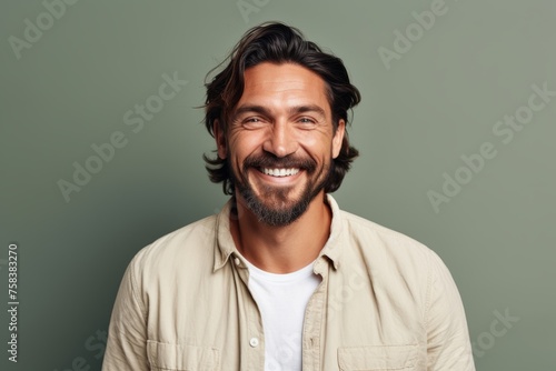 Handsome man in casual clothes smiling at camera while standing against grey background