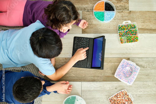 Children engaging in creative play with beads and laptop photo