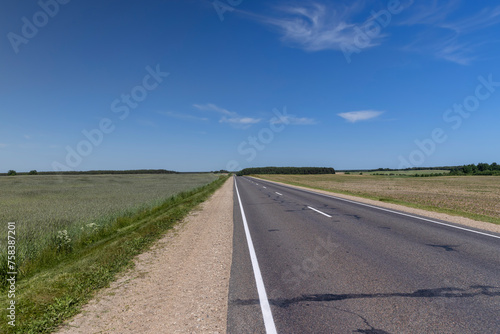 paved narrow road in a straight line through the field