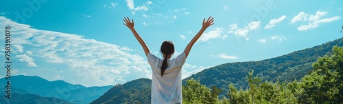 A person wearing white is standing with their arms raised in front of the mountains, facing away from us and enjoying nature's beauty under bright sunlight Generative AI