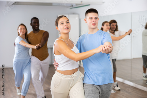 Man and woman in pairs learning to dance waltz in modern studio