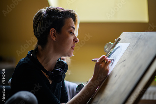 Side view of professional illustrator pencil drawing portrait at home.